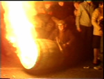 A man admires his blazing tar barrel